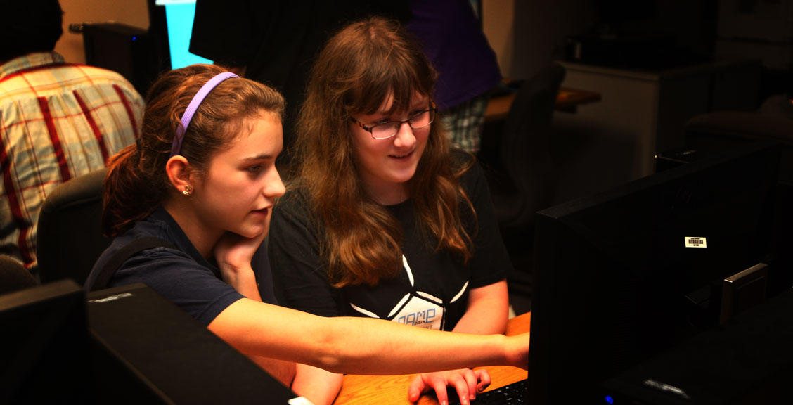 two smiling girls working together at a computer